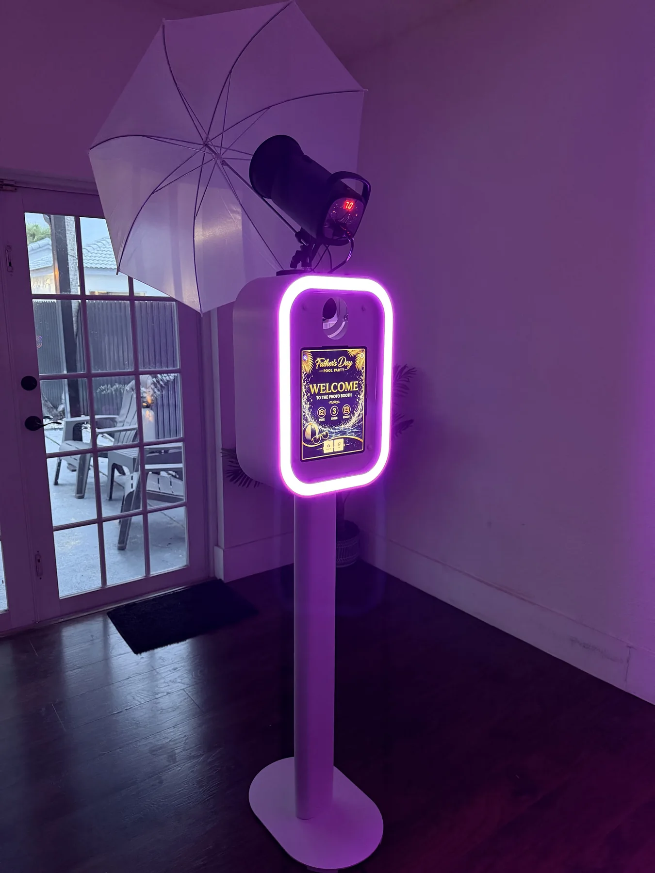 White DSLR photo booth with studio umbrella and magenta lighting